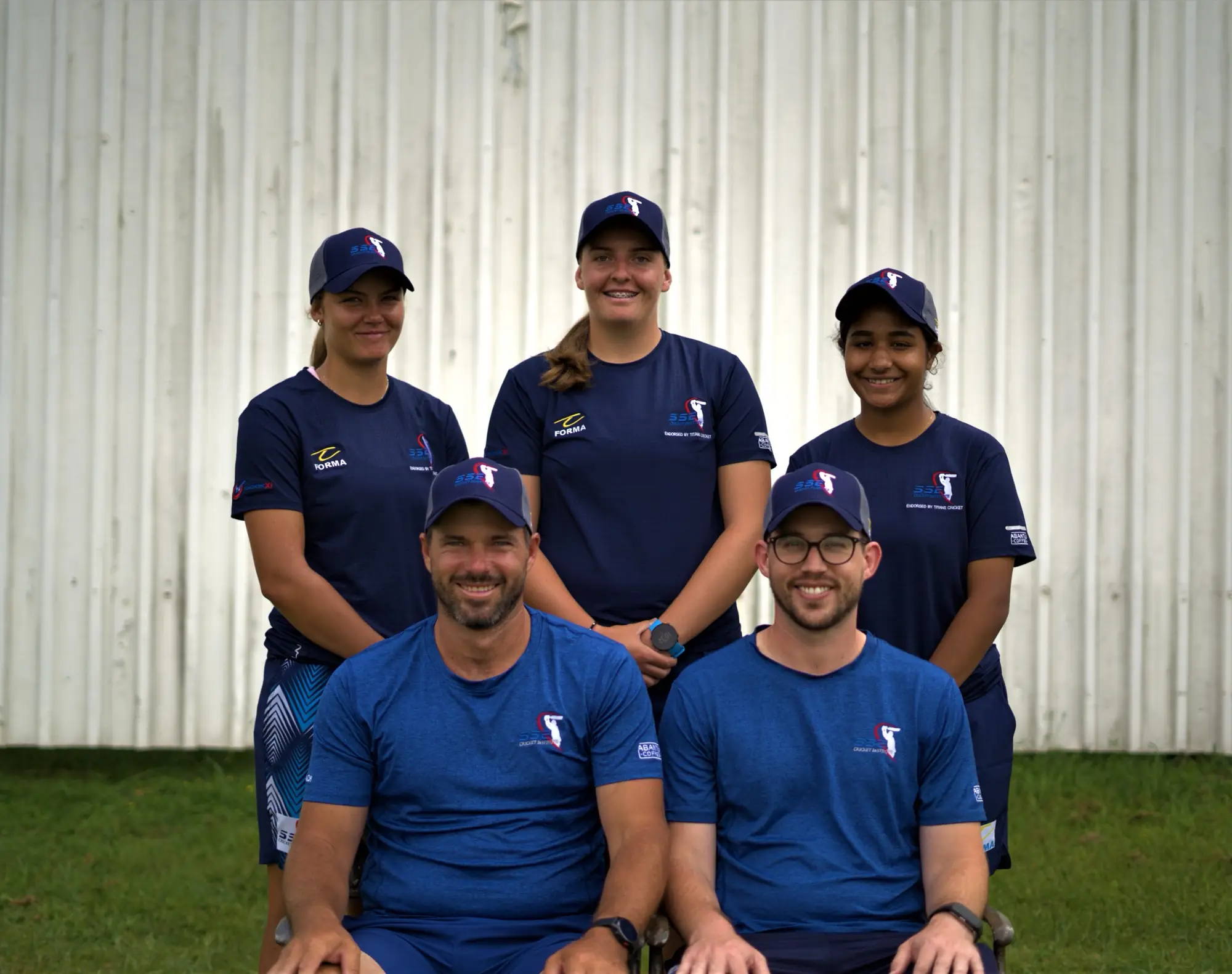 Smiling SSE players standing behind two seated coaches, all in SSE kit