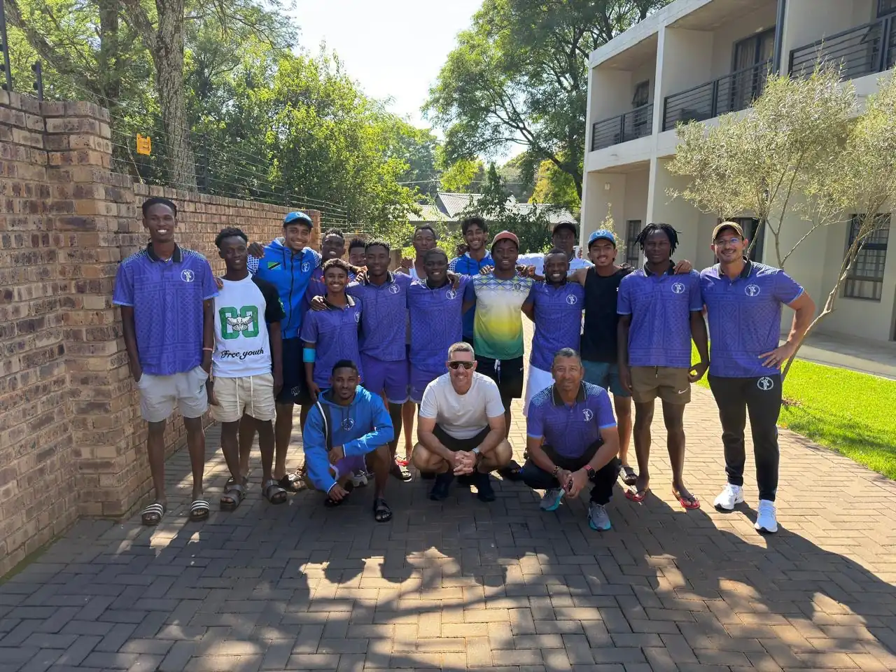 A visiting touring squad in matching kit and their coaches gathered together outside their accommodation