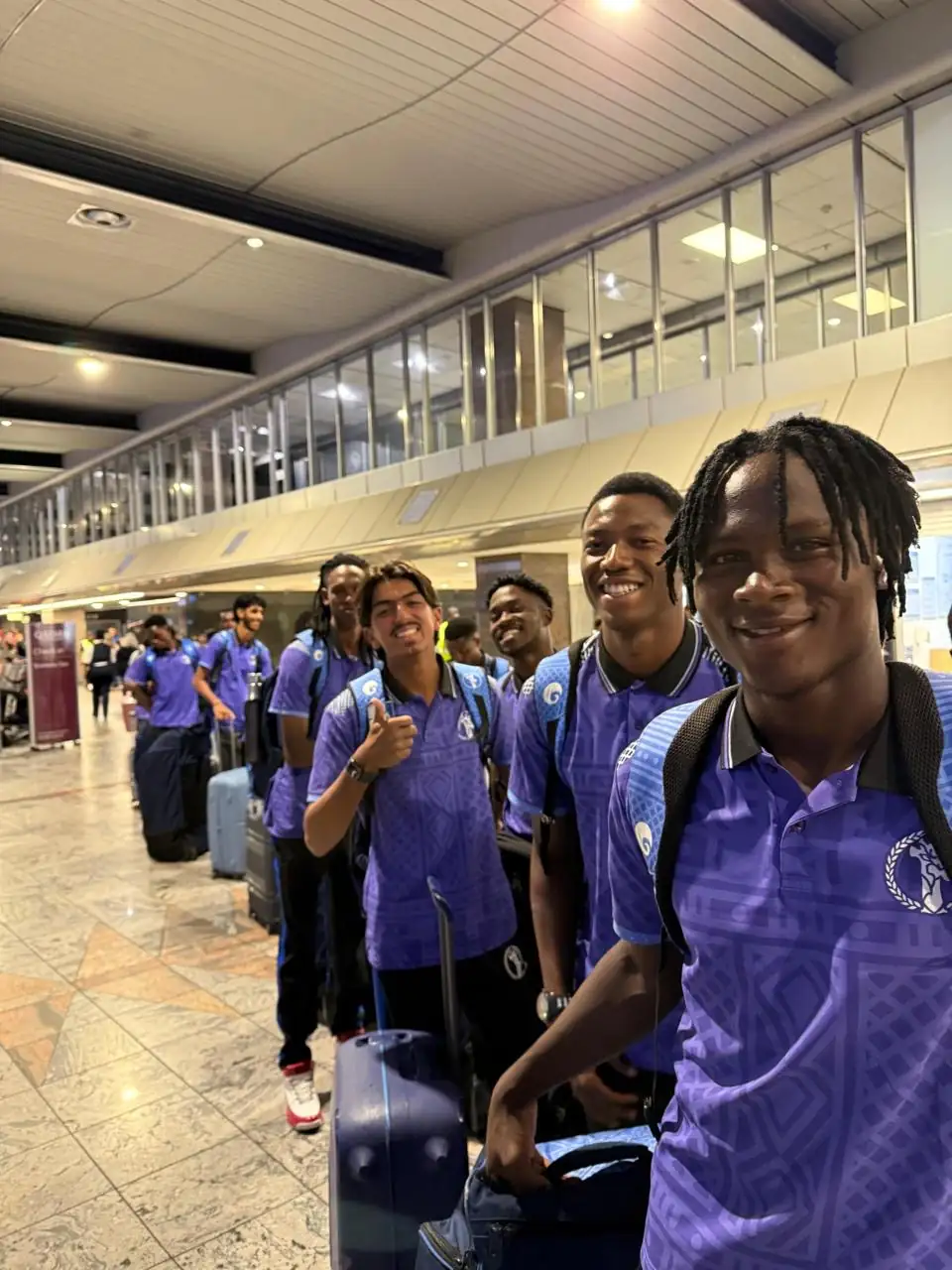 Smiling touring players with their luggage after landing at the airport